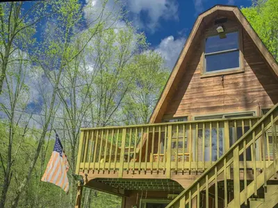 a house with a wrap around deck with a flag at Magnificent A-Frame Cabin Rental in the Trees close to Hocking Hills State Park, Ohio in Laurelville
