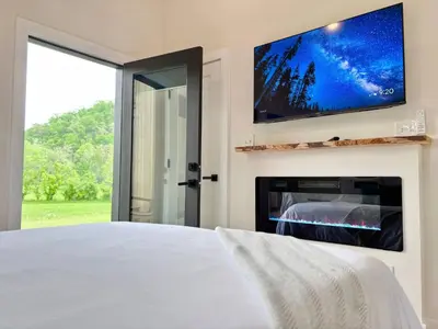 a bedroom with a tv and a fireplace at Knob Hill at Three Suns Cabins in Stanton