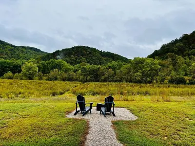 two chairs sitting next to a table in a field at Knob Hill at Three Suns Cabins in Stanton