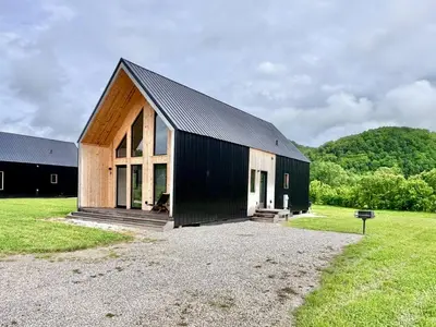 a black and wooden building in a field at Knob Hill at Three Suns Cabins in Stanton
