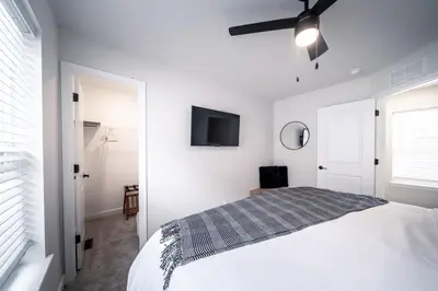 a white bedroom with a bed and a tv on the wall at Arcade Game Room! Luxury New 3BR CLE Clinic UnivCircle Little Italy in Cleveland