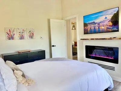 a bedroom with a white bed and a fireplace at Wildflower Walk at Three Suns Cabins in Stanton