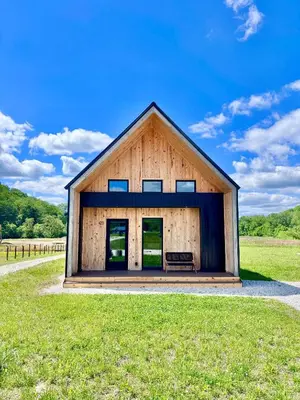 a barn house with a bench in a field at Wildflower Walk at Three Suns Cabins in Stanton