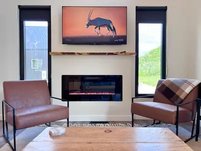 a living room with a fireplace with a tv and a deer on the wall at Wildflower Walk at Three Suns Cabins in Stanton