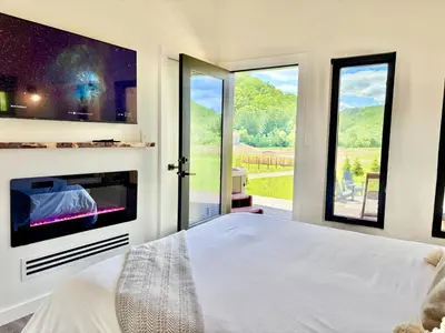 a bedroom with a bed and a large window at Wildflower Walk at Three Suns Cabins in Stanton