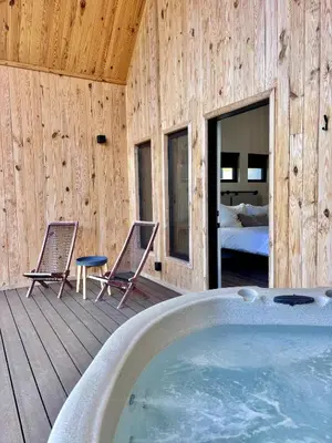 a room with a hot tub and two chairs on a deck at Wildflower Walk at Three Suns Cabins in Stanton