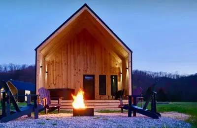 a log cabin with a fire in front of it at River's Edge at Three Suns Cabins in Stanton