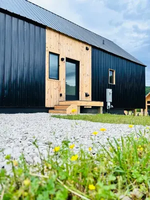 a black and wooden building with a bench in front of it at Trail Tamer at Three Suns Cabins in Stanton