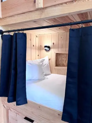 a bed in a wooden room with blue curtains at Moonrise Meadow at Three Suns Cabins in Stanton