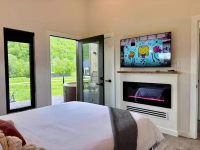 a bedroom with a bed and a flat screen tv at Moonrise Meadow at Three Suns Cabins in Stanton