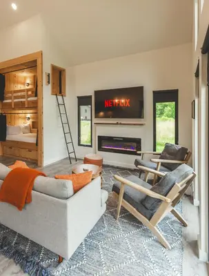 a living room with a couch and chairs and a tv at Moonrise Meadow at Three Suns Cabins in Stanton