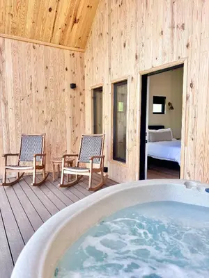 a hot tub on a deck with two chairs and a bed at Perfect Perch at Three Suns Cabins in Stanton