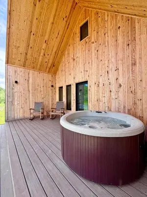 a wooden building with a hot tub on a deck at Perfect Perch at Three Suns Cabins in Stanton