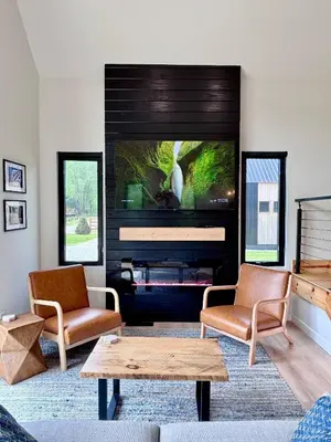 a living room with a large television and two chairs at Perfect Perch at Three Suns Cabins in Stanton