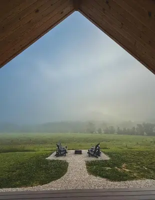 two benches in a park with a view of a field at River Rascal at Three Suns Cabins in Stanton