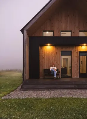 a man sitting on a bench outside of a barn at River Rascal at Three Suns Cabins in Stanton