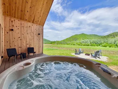 a hot tub on a deck with a view of a field at River Rascal at Three Suns Cabins in Stanton
