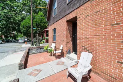 two white chairs sitting outside of a brick building at Cozy Condo On Collins- Walk to High St /Dtown /OSU in Columbus