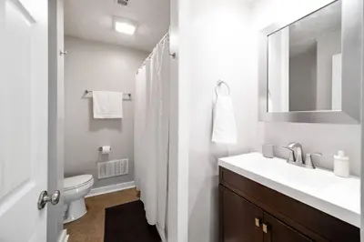 a bathroom with a sink and a toilet and a mirror at Cozy Condo On Collins- Walk to High St /Dtown /OSU in Columbus