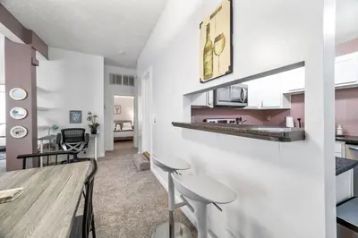 a kitchen and dining room with a table and stools at Cozy Condo On Collins- Walk to High St /Dtown /OSU in Columbus