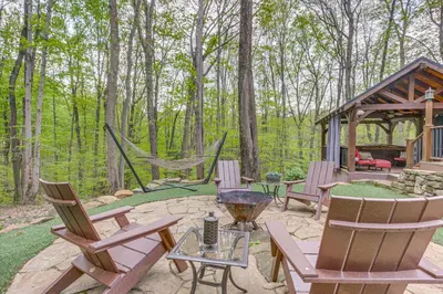 a patio with chairs and a hammock in the woods at Hocking Hills Social Distance Cabin with Hot Tub in Laurelville