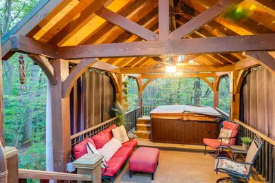 a screened in porch with a red couch and a tub at Hocking Hills Social Distance Cabin with Hot Tub in Laurelville