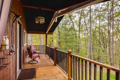 a porch of a cabin with a red chair on it at Hocking Hills Social Distance Cabin with Hot Tub in Laurelville