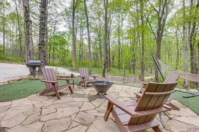 a group of chairs and a grill in the woods at Hocking Hills Social Distance Cabin with Hot Tub in Laurelville