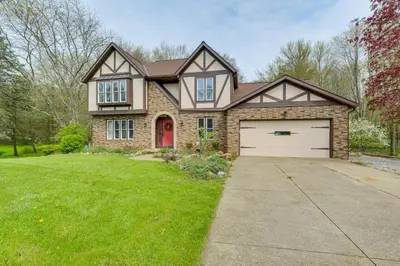 a brick house with a red door and a garage at Bike, Fish, Golf and More Stately Tudor in Mogadore in Uniontown