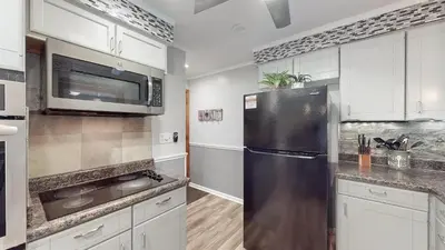 a kitchen with a stainless steel refrigerator and white cabinets at Sideline Sanctuary: Cozy Nights, Game Day Lights in Canton
