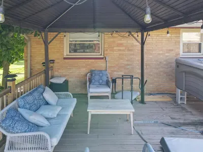 a patio with a couch and chairs under a black roof at The Blitz House-Where Legends Unwind in Canton