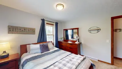 a bedroom with a bed and a dresser and a mirror at Snap, Set, Stay-Game Day Comfort Near It All in Canton
