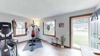 a gym with exercise equipment in a room with windows at Snap, Set, Stay-Game Day Comfort Near It All in Canton