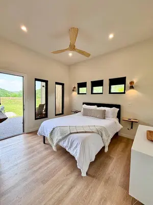 a bedroom with a large bed and a large window at Three Suns Full Rental | 8 Cabins | Views | River in Stanton