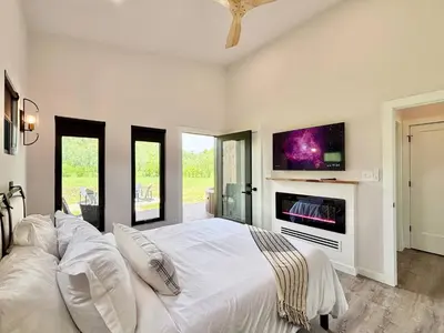 a bedroom with a white bed and a fireplace at Three Suns Full Rental | 8 Cabins | Views | River in Stanton