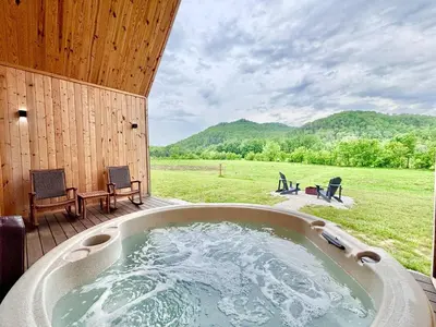 a hot tub on a deck with a view of a field at Three Suns Full Rental | 8 Cabins | Views | River in Stanton