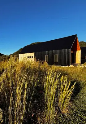 a barn with a black roof sitting on top of a field at Three Suns Full Rental | 8 Cabins | Views | River in Stanton