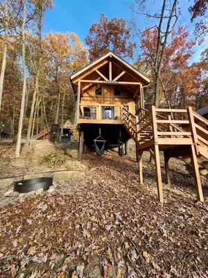 a large wooden house in the middle of a forest at Sweet Tree Cabin with Grill Overlooking Tappan Lake in Ohio in Deersville