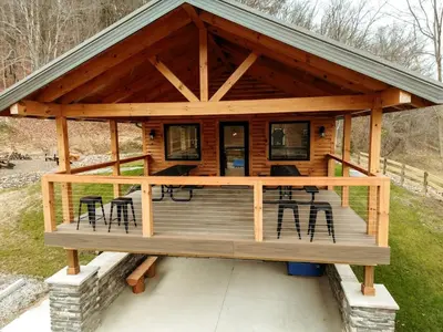 a log cabin with a deck with chairs and tables at Sweet Tree Cabin with Grill Overlooking Tappan Lake in Ohio in Deersville