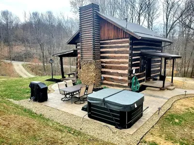 a log cabin with a table and a grill at Renovated Cottage with Spa Surrounded by Beautiful Hiking Trails by Tappan Lake in Ohio in Deersville