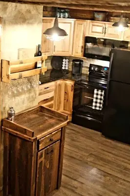 a kitchen with a black refrigerator and wooden cabinets at Renovated Cottage with Spa Surrounded by Beautiful Hiking Trails by Tappan Lake in Ohio in Deersville
