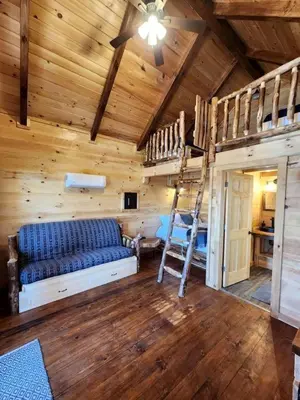 a room with a couch and bunk beds in a cabin at Lofted Cabin Wonderful for Outdoor Adventures near Tappan Lake in Ohio in Deersville