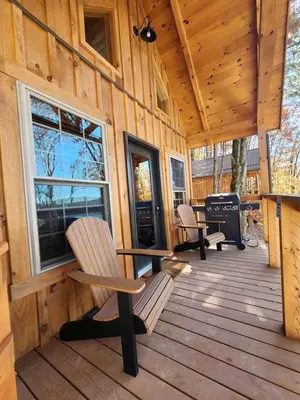 a cabin with two chairs and a grill on a deck at Lofted Cabin Wonderful for Outdoor Adventures near Tappan Lake in Ohio in Deersville