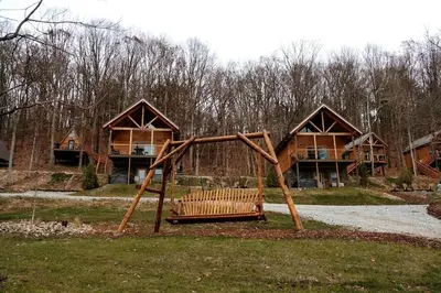 a park with a wooden swing in front of a house at Lofted Cabin Wonderful for Outdoor Adventures near Tappan Lake in Ohio in Deersville