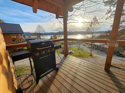 a grill on a deck with a view of a river at Modern Spacious Cabin near Tappan Lake with Jacuzzi and Panoramic Views in Ohio in Deersville