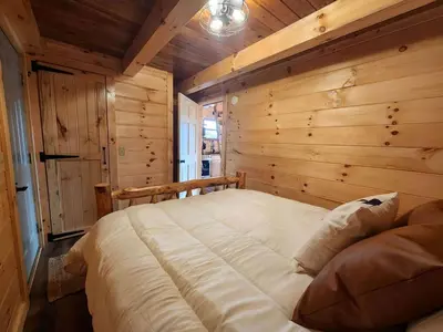 a bedroom with a large bed in a wooden wall at Luminous Cabin near Tappan Lake with Hot-Tub, BBQ and Deck in Ohio in Deersville