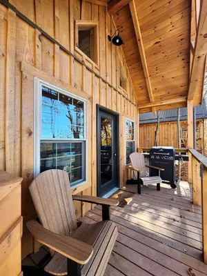a cabin with a bench and a grill on a deck at Wooden Chic Cabin Fully Stocked near Tappan Lake in Ohio in Deersville