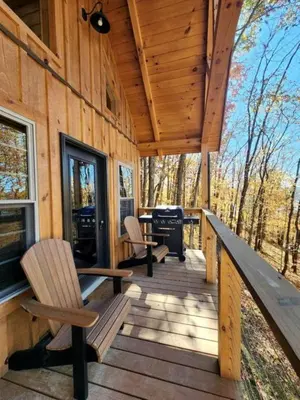 a porch of a cabin with chairs and a grill at Gorgeous Cabin Great for Family Getaways by Tappan Lake in Ohio in Deersville