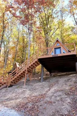 a cabin in the woods with a wooden staircase at Romantic A-frame Cabin Ideal for Two by Tappan Lake in Ohio in Deersville