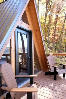 a porch of a cabin with two chairs and a door at Romantic A-frame Cabin Ideal for Two by Tappan Lake in Ohio in Deersville